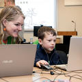 Researcher and child using laptops in a workshop