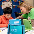 Child and researcher looking at blue ipad together