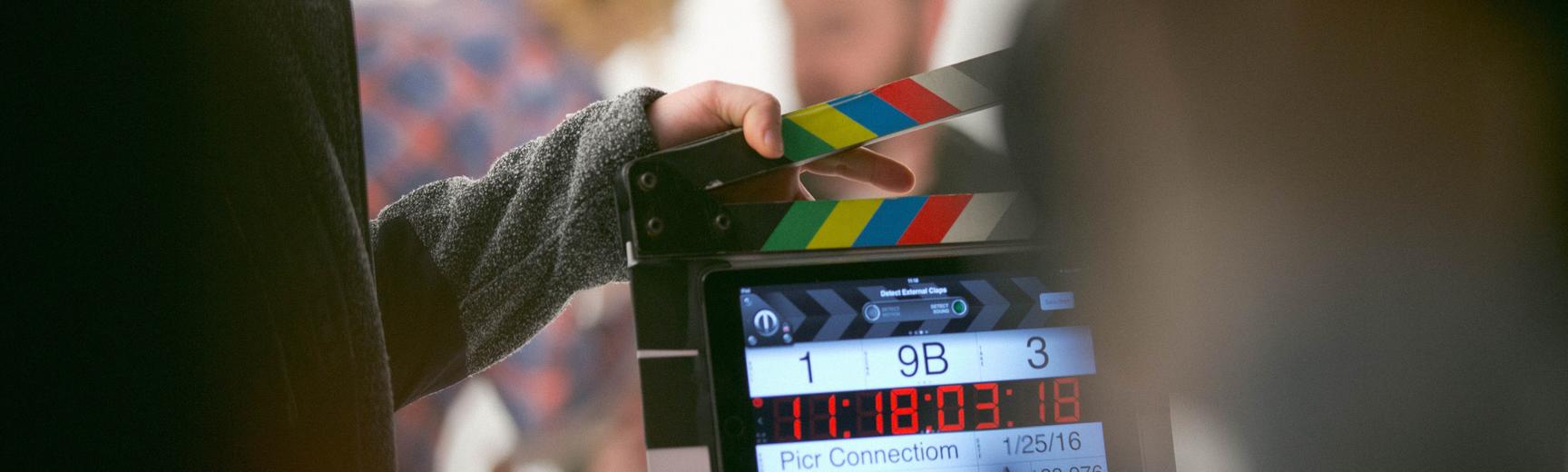 A film crew holds a clapperboard in front of actors on set