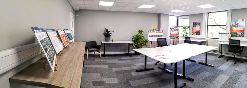 Oxford SDG Impact Lab A bright-lit room with tables and chairs arranged for collaborative working, with easyjet-branded images displayed on easels, and several green plants scattered around the room.