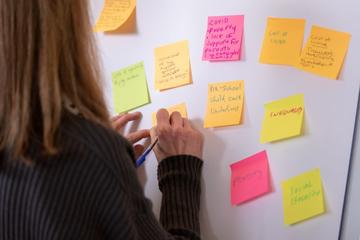 A delegate adds her thoughts to a board covered in post-it notes about the challenges facing early years provision